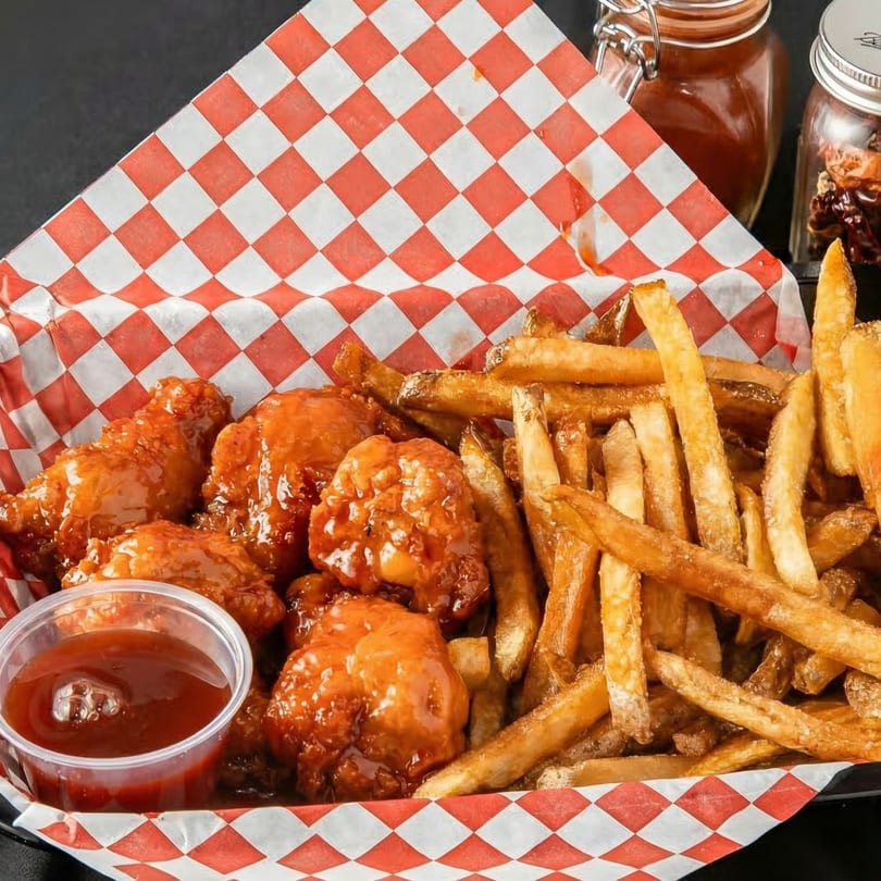 A basket of Chicago's Best chicken wings and french fries with a side of dipping sauce.