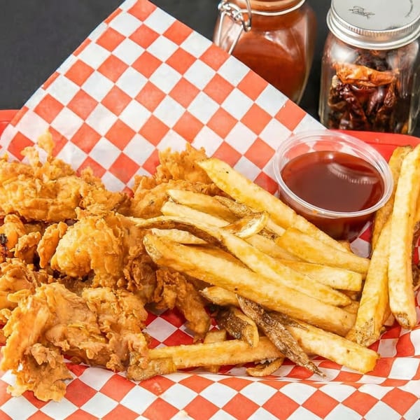 Crispy fried chicken and golden french fries in a red and white checkered basket with ketchup.