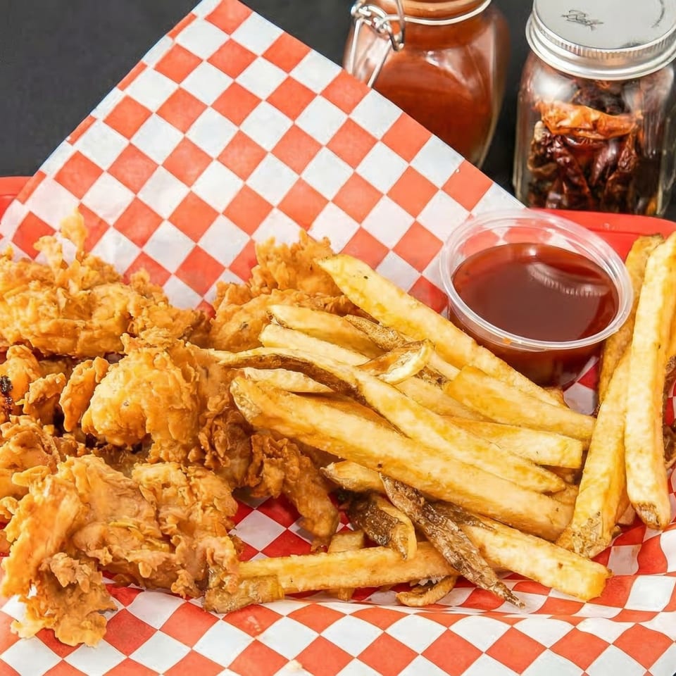 Crispy fried chicken and golden french fries in a red and white checkered basket with ketchup.
