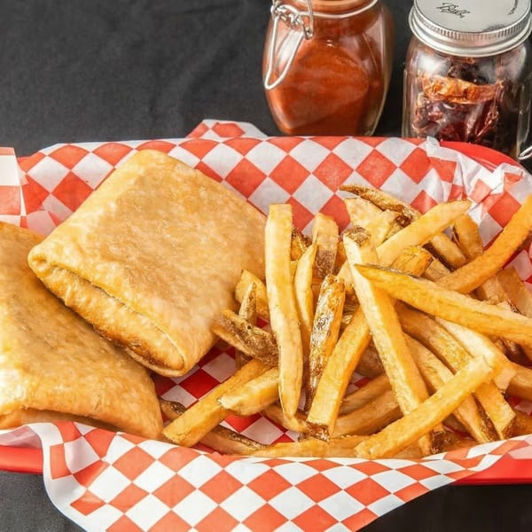 Golden-brown burritos and a pile of crispy french fries in a red and white checkered basket.