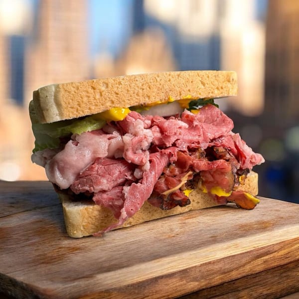 A Chicago's Best pastrami sandwich with mustard, lettuce, and onions on a wooden board.